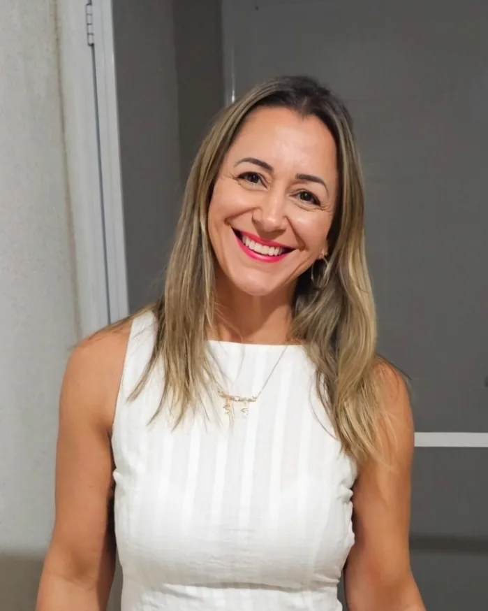 Fabiana Sgarbi sorrindo, de cabelos longos e blusa branca